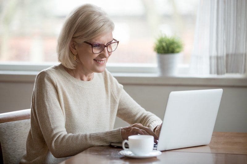 Ältere Frau mit Brille vor einem Laptop